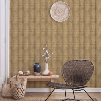 A room with beige cane wallpaper featuring a woven effect. The room is staged with a wicker chair, decorative baskets, and a wooden bench with decorative items on top.