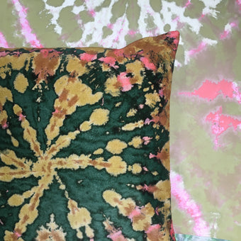 A tie-dye patterned velvet cushion in green, yellow, and pink hues.