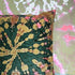 A tie-dye patterned velvet cushion in green, yellow, and pink hues.