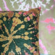 A tie-dye patterned velvet cushion in green, yellow, and pink hues.